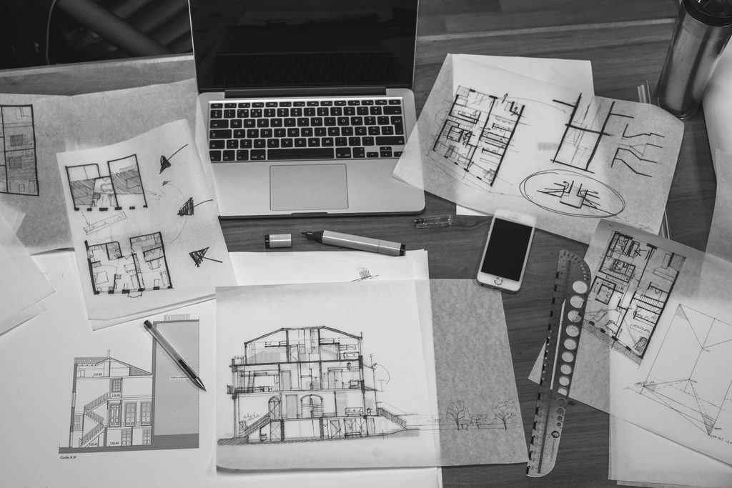 Mesa de trabajo de un estudio de arquitectura con planos, regla y útiles de dibujo — estrategia SEO para arquitectos