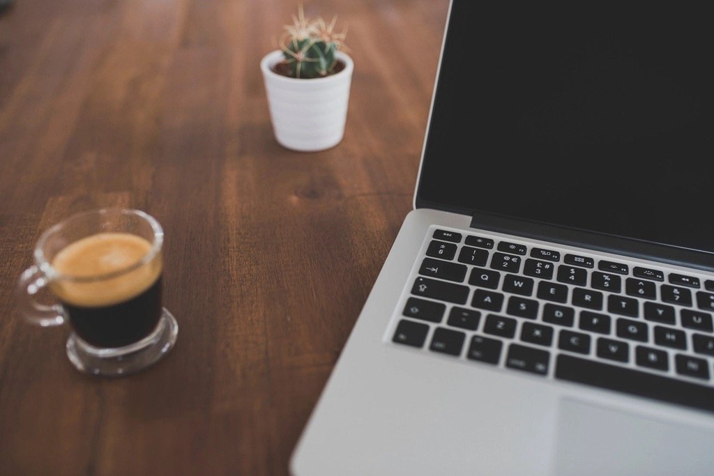 Escritorio de trabajo con ordenador y café - cómo elegir el dominio adecuado para tu empresa