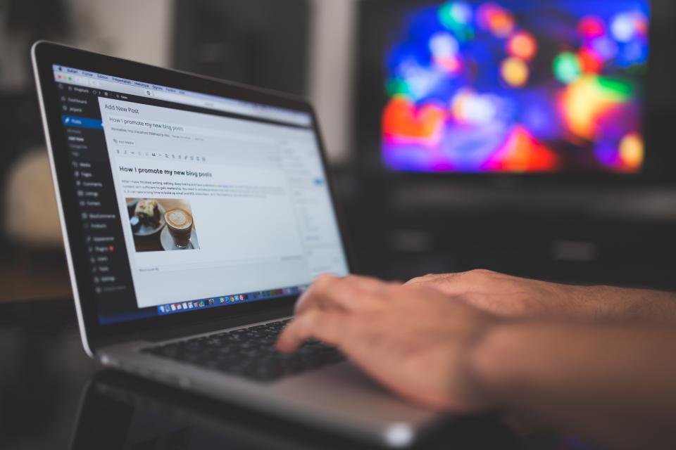 Portatil abierto con un blog corporativo en pantalla junto a una libreta de planificacion - estrategia de contenidos para blog corporativo