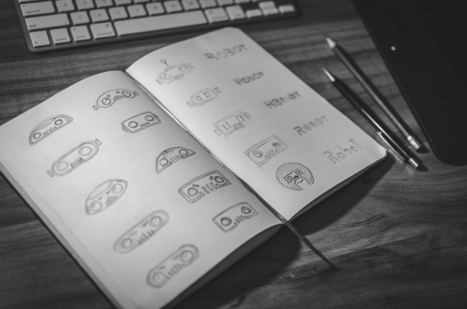 Cuaderno con bocetos de logotipos sobre una mesa de trabajo - construir una identidad de marca desde cero