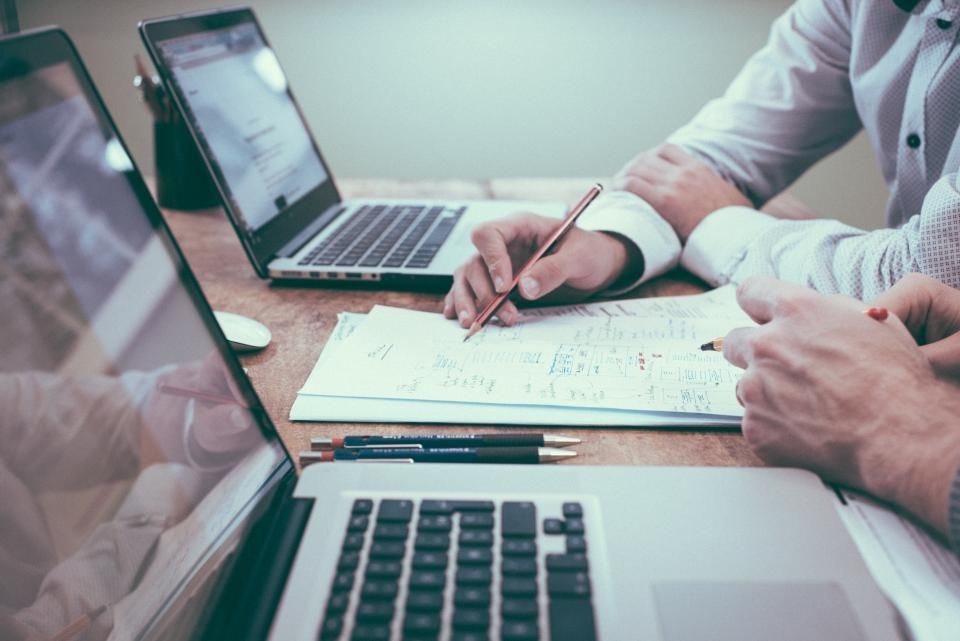 Dos profesionales revisando documentos y anotando sobre papel durante una auditoria de marca