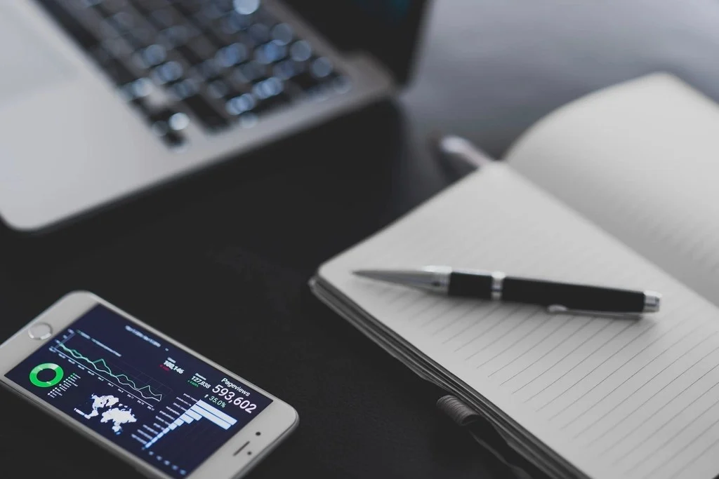 Móvil con gráficos junto al teclado de un ordenador