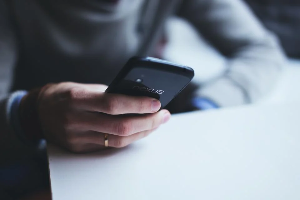 Persona utilizando su teléfono móvil en una mesa